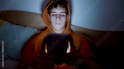 4k medium handheld shot of teenager using a smartphone lying in bed late at night, playing games, watching videos, and scrolling the screen.Children's screen addiction.Screen Addiction in Youth