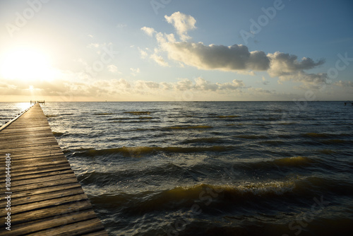 Fotografie Long wooden pier over water leading to the sunrise and horizon on the Gulf of Me