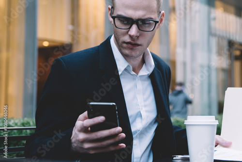 Young businessman with papers browsing smartphone photo