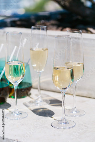 Champagne flutes and colorful tumblers set outdoors, capturing a refreshing and stylish atmosphere perfect for a summer celebration or social event