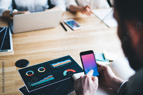 Anonymous entrepreneur using smartphone near colleagues