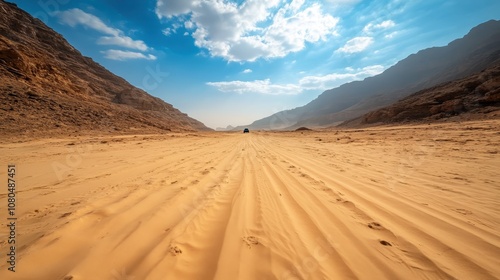 A single vehicle traverses a vast desert, framed by towering mountain ranges under a sky filled with clouds, highlighting themes of adventure and solitude. photo