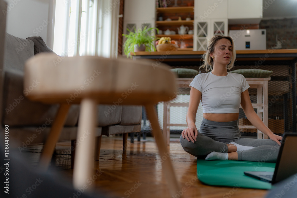 Smiling woman in athletic wear attending virtual yoga session in cozy living room. Smiling woman in athletic wear attending virtual yoga session in cozy living room.