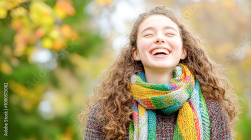 Joyful Young Woman Smiling Brightly in a Colorful Scarf Surrounded by Autumn Foliage