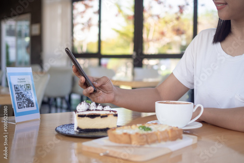 Woman use smartphone to scan QR code for order menu in cafe restaurant with a digital delivery. Choose menu and order accumulate discount. E wallet, technology, pay online, credit card, bank app.. photo