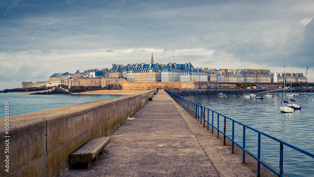 Vue de Saint Malo Intra Muros depuis la digue sous un ciel nuageux Vue de Saint Malo Intra Muros depuis la digue sous un ciel nuageux