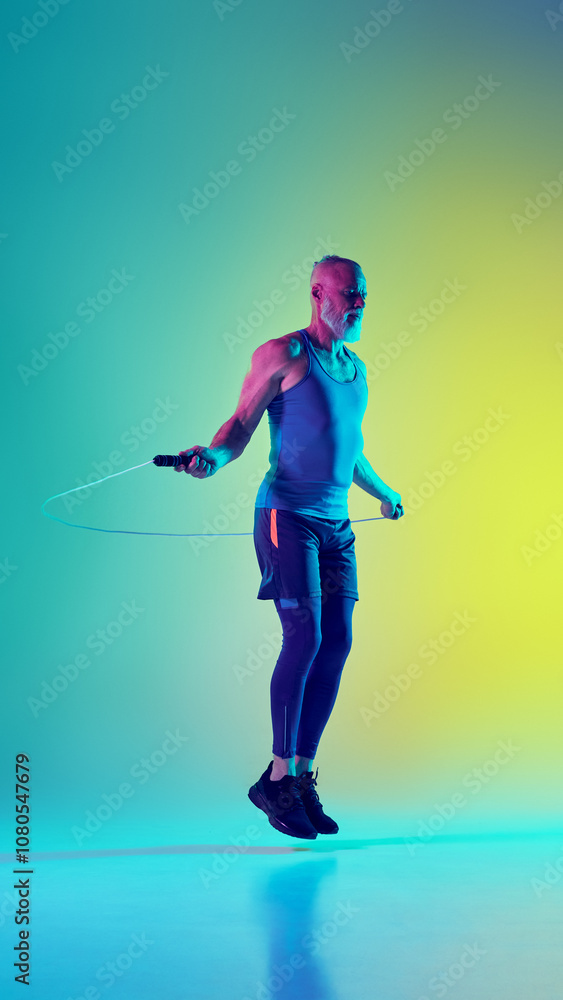 Full-length side view vertical image of elderly man in sportswear training, jumping rope against gradient green yellow background in neon light. Concept of sport, active elderly lifestyle, health care Full-length side view vertical image of elderly man in sportswear training, jumping rope against gradient green yellow background in neon light. Concept of sport, active elderly lifestyle, health care