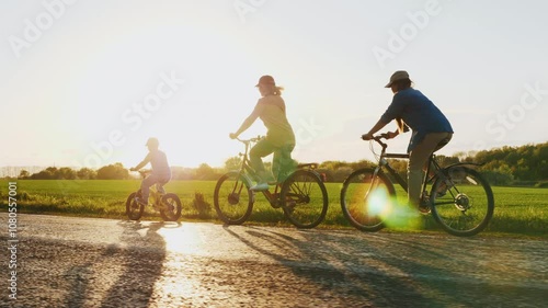 A family rides bicycles along a road at sunset, enjoying an evening in nature