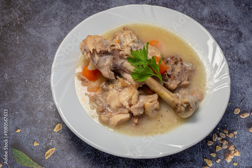 Boiled chicken thighs with potatoes and carrots in a white plate. Boiled chicken meat.