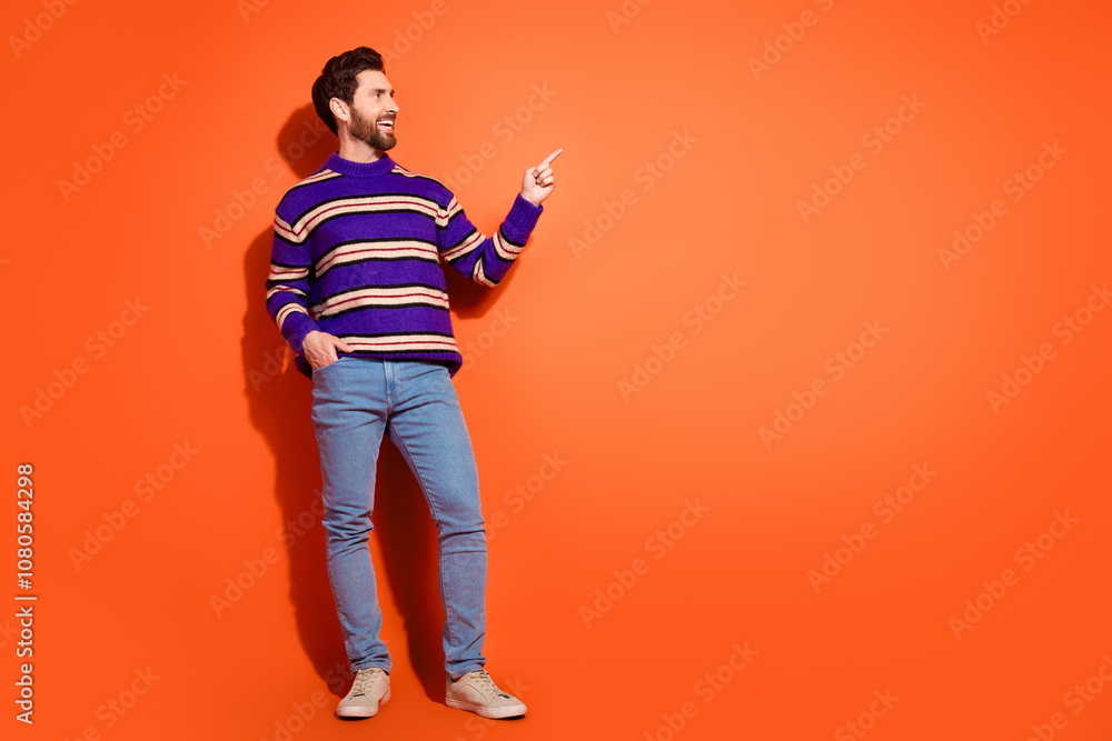 Fototapeta premium Full body photo of attractive young man point look empty space dressed stylish striped purple clothes isolated on orange color background