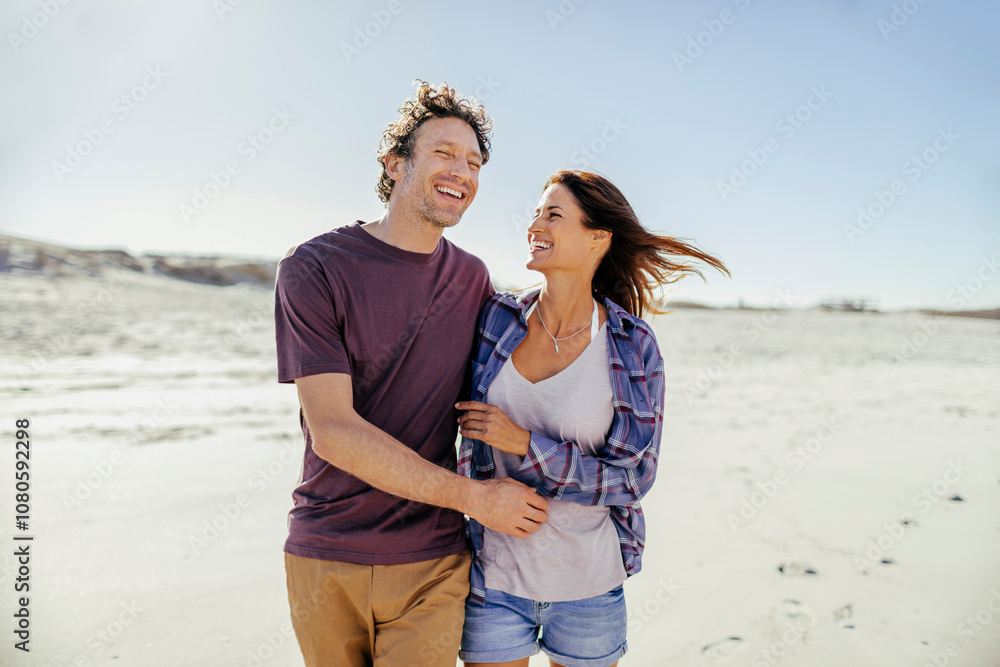 © Marko Geber - Happy couple walking on the beach together on a sunny day