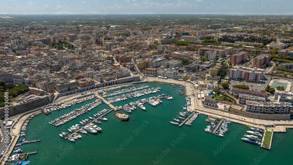 Obraz premium Aerial view of the historic center of Bisceglie, in Puglia, Italy. In the foreground is the tourist port, with many boats anchored, located on the Mediterranean Sea.