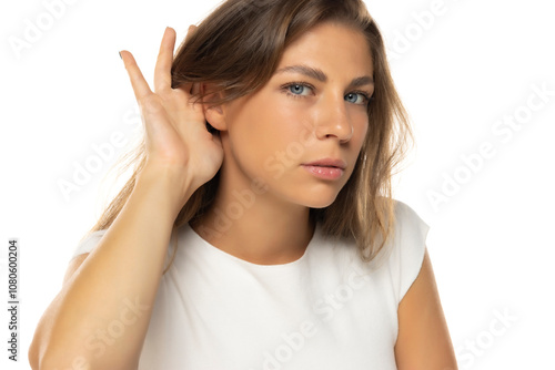 Young woman over isolated background listening to something by putting hand on the ear.