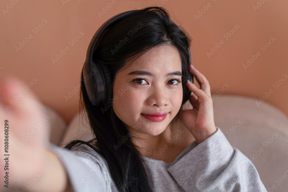 Asian girl wearing headphones enjoying music very comfortably on the sofa Asian girl wearing headphones enjoying music very comfortably on the sofa