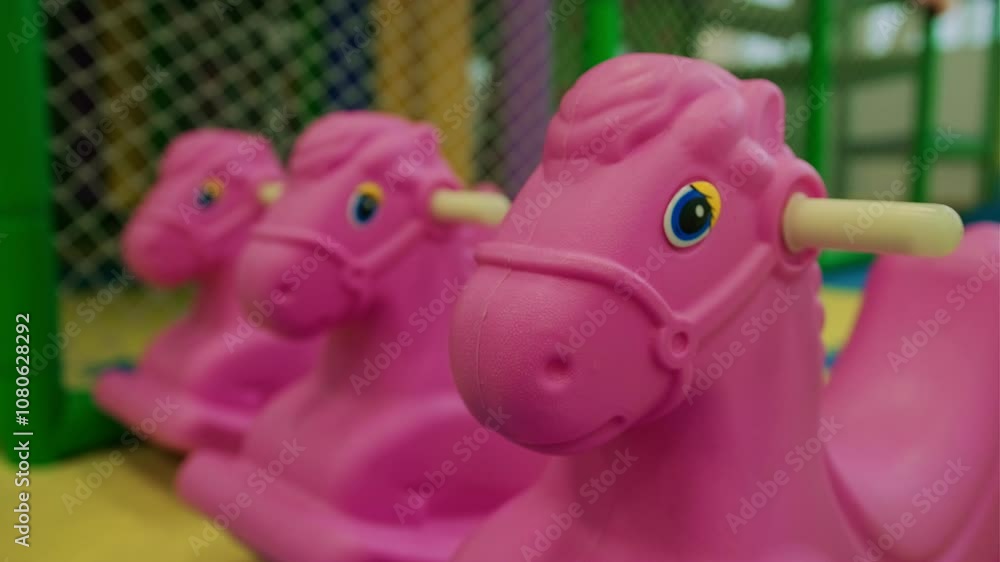 custom made wallpaper toronto digitalThree pink rocking horses sit in a vibrant indoor play area designed for children, featuring colorful flooring and safety nets, creating a fun atmosphere.
