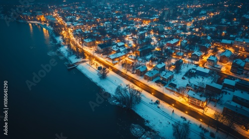 Fototapeta Naklejka Na Ścianę i Meble -  Aerial view of a small town at night, with snow-covered streets and a river flowing through it.