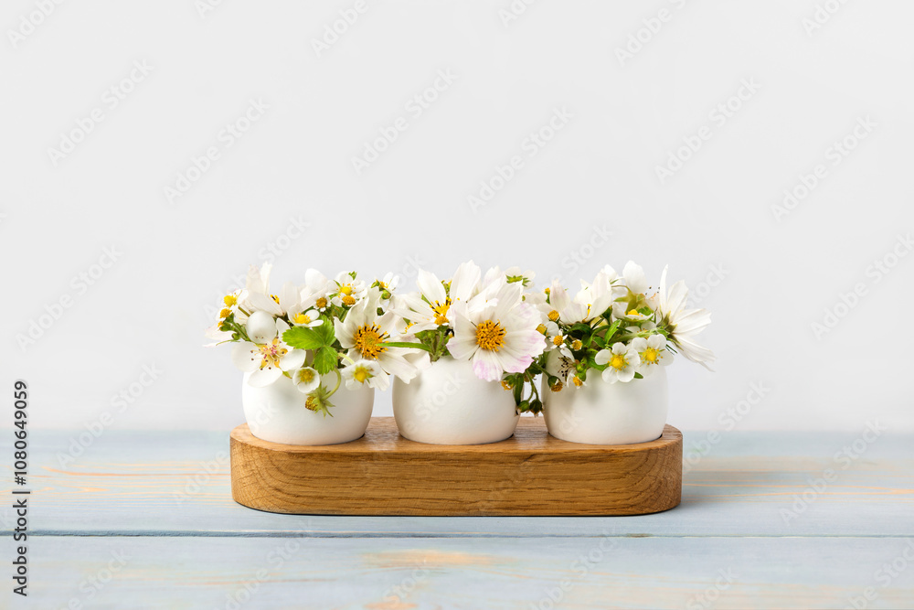 White eggs in wooden stands with spring pear and strawberry flowers on a blue wooden table. Happy Easter White eggs in wooden stands with spring pear and strawberry flowers on a blue wooden table. Happy Easter
