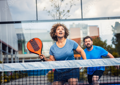 Mixed adult couple palying padel on outdoor court.