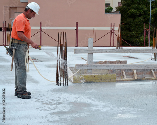 Bilde på lerret Construction carpenter waters the surface of a reinforced concrete floor slab on a construction site