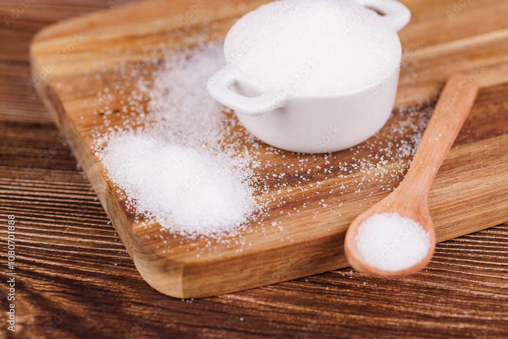 Top view of a wooden table with a ceramic bowl filled with sugar and a wooden spoon beside it, placed on a wooden surface Top view of a wooden table with a ceramic bowl filled with sugar and a wooden spoon beside it, placed on a wooden surface