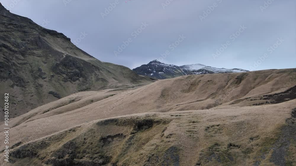 A mountain range with a cloudy sky in the background. The mountains are covered in snow and the sky is overcast A mountain range with a cloudy sky in the background. The mountains are covered in snow and the sky is overcast