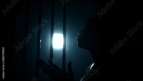 African American woman prays to god on dark prison. Cinematic effect photo