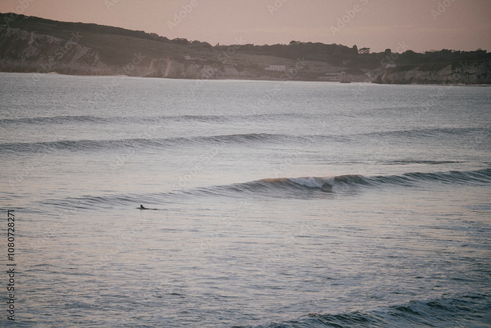 Shot of the island in the sea and people swimming in the sea at evening Shot of the island in the sea and people swimming in the sea at evening