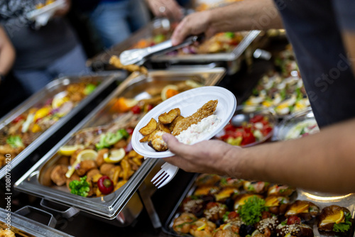 Obraz na płótnie Delicious buffet spread featuring a variety of dishes, with a hand selecting fri