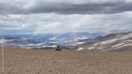 Aerial drone shot of man riding his bike on the mountain cliff in ladakh