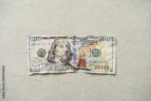 a crumpled 100 dollar bill, currency concept, isolated on grey background.