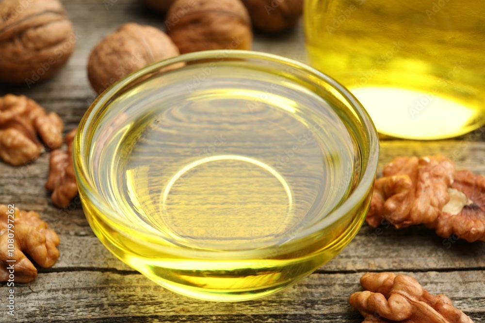 Cooking oil in bowl and walnuts on wooden table, closeup Cooking oil in bowl and walnuts on wooden table, closeup