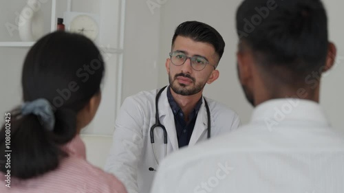 Indian Couple getting professional medical consultation during visit of GP doctor. Childbirth problem and solutions, reproductive and fertility issues diagnostics, medicare and insurance. Doctor help