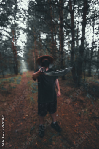 A masked man stands in a forest holding a katana. A samurai points a katana at the camera while standing in the forest. The image is blurry and mysterious, creating a sense of danger and intrigue.