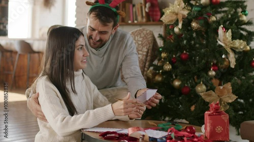 A young loving couple is writing to do list and goals on a blank paper sheet for the New Year and Christmas. 4k video