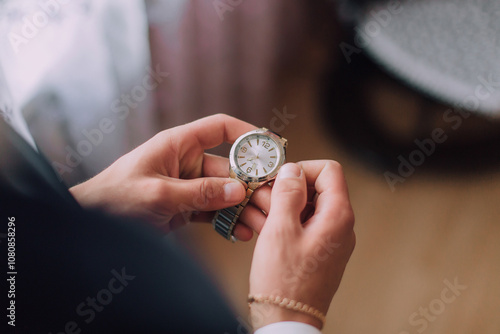 A person is holding a watch and looking at it. The watch is gold and has a black face