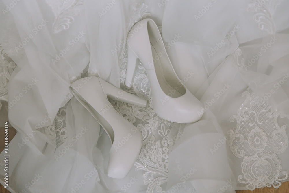 A pair of white high heels are on a white dress. The dress is white and has lace A pair of white high heels are on a white dress. The dress is white and has lace