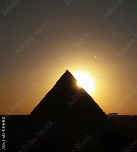 sillouete  pyramid .sunset behind pyramids of giza  egypt. clear sky and half sun