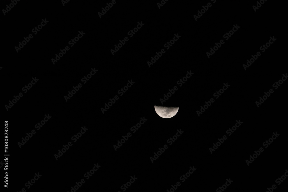 A stunning view of a half moon illuminated against a dark sky, showcasing the beauty of the celestial night. A stunning view of a half moon illuminated against a dark sky, showcasing the beauty of the celestial night.