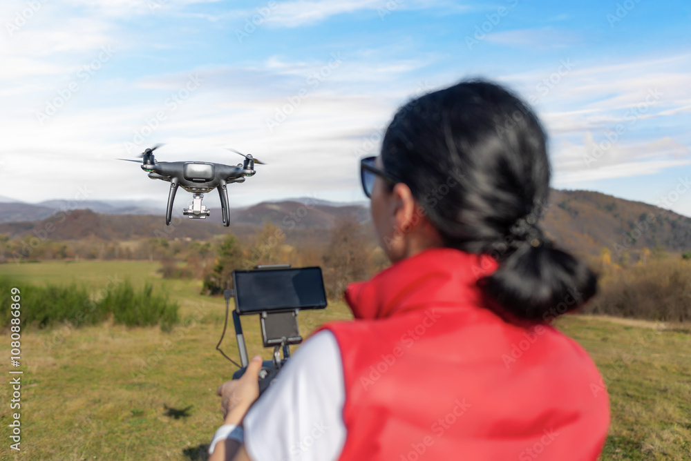 A young woman controls a drone with a remote control in her hands.