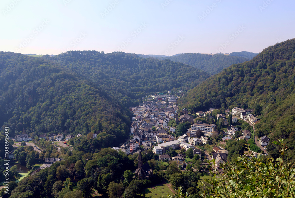 Obraz premium Der Kurort Bad Bertrich in der Eifel im Landkreis Cochem-Zell zwischen bewaldeten Hügeln. Aussicht vom Wanderweg Wasserfall-Erlebnisroute, der 2023 zu Deutschlands schönstem Wanderweg gewählt wurde.