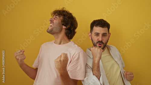 Men celebrating together against a yellow background, showcasing friendship and joy in an isolated setting