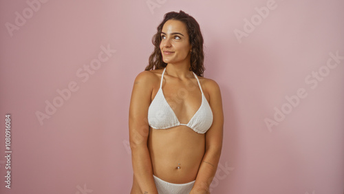 Attractive woman posing in a bikini against a pink background