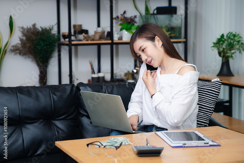 Businesswoman talking on phone working on laptop in modern office. Sharing good business news. Woman working on laptop at office while talking on phone.