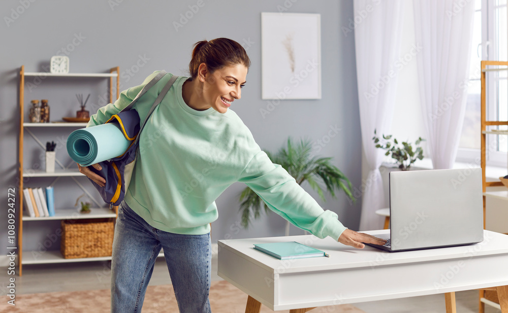 Young athlete woman with sports bag with equipment and sportswear, turning off laptop on desk, going to outdoor workout or gym. Smiling positive girl leaving home ready for training session. Young athlete woman with sports bag with equipment and sportswear, turning off laptop on desk, going to outdoor workout or gym. Smiling positive girl leaving home ready for training session.