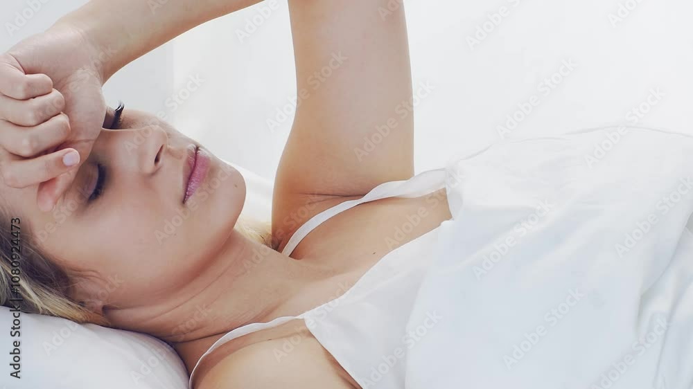 Young woman lying in the bed. Beautiful blond sleeping girl. Morning in the bedroom, daylight from the window. Young woman lying in the bed. Beautiful blond sleeping girl. Morning in the bedroom, daylight from the window.