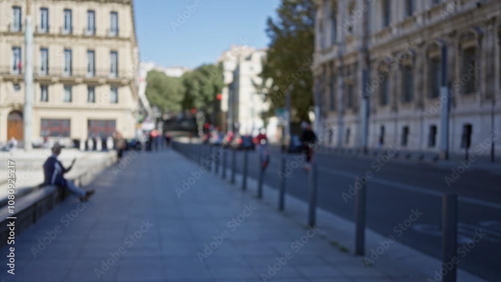 Naklejka premium Blurred scene of a man on a street in marseille with historic architecture and trees in the distance, creating a defocused, bokeh cityscape background.