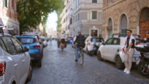 Photography Blurry city street scene in rome, italy with bokeh effect, featuring people, cars parked, and cobblestone road in the old town, creating a nostalgic urban atmosphere
