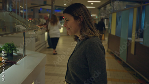 Woman smiling indoors at buffet restaurant, highlighting young hispanic woman enjoying meal selection in a warm, inviting atmosphere with diverse food options.