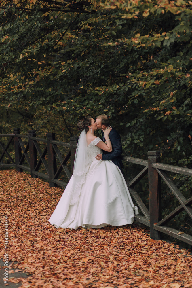 A bride and groom are kissing in front of a fence. The bride is wearing a white dress and the groom is wearing a blue suit. Scene is romantic and intimate A bride and groom are kissing in front of a fence. The bride is wearing a white dress and the groom is wearing a blue suit. Scene is romantic and intimate