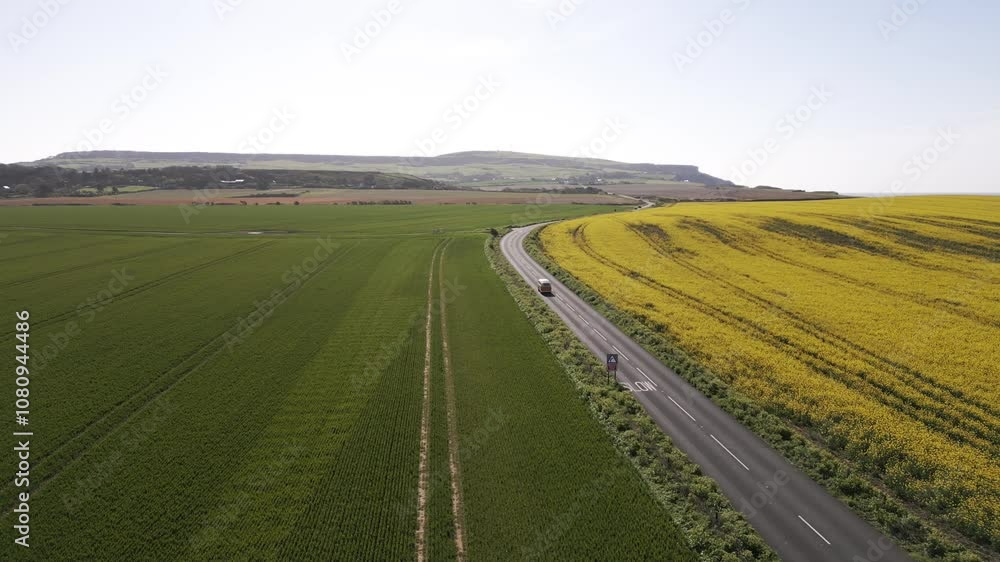 Aerial view of a hill and a farm land and a road between them Aerial view of a hill and a farm land and a road between them
